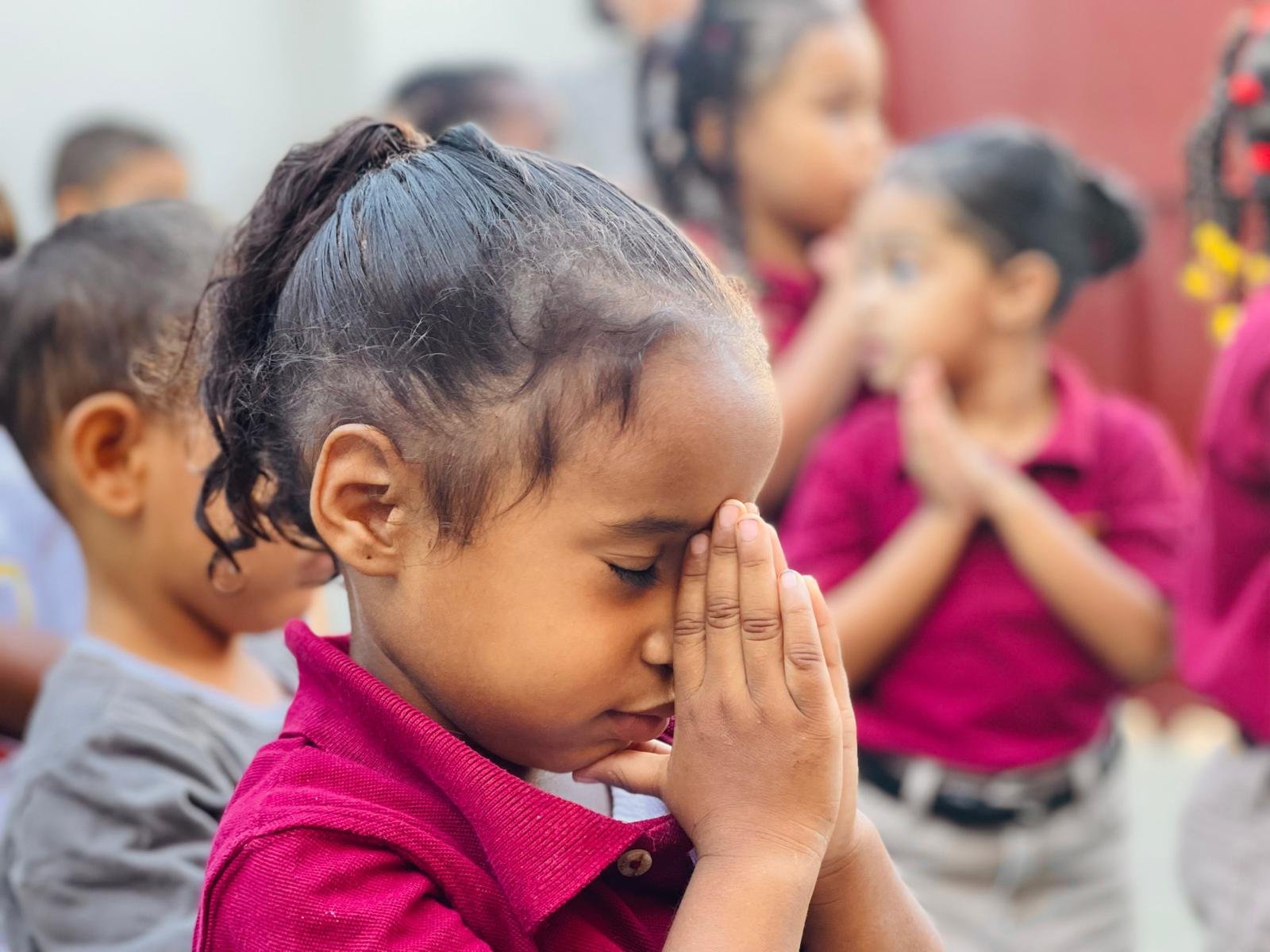 A young child bows their head in prayer